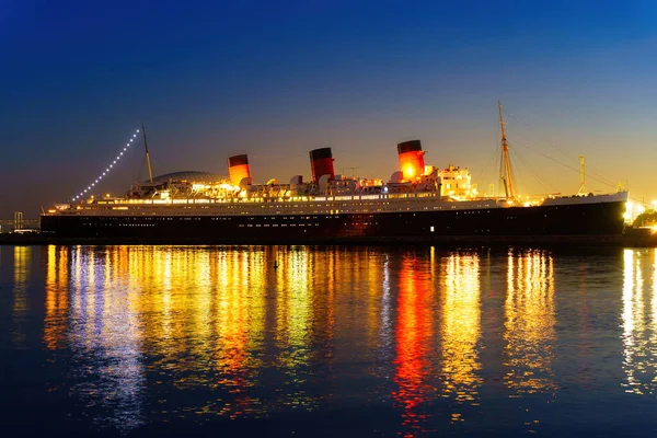 由五彩缤纷的灯光照亮的历史性玛丽女王号船迷人的夜景映照在长滩港湾平静的水面上 — 图库照片