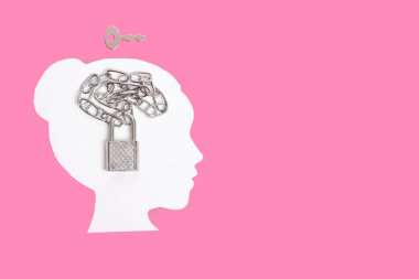 Beyaz kadının kafasında zincirli asma kilit şekli ve pembe arka planda kopyalanmış bir anahtar var. Beyin gücü kavramını serbest bırakmak.
