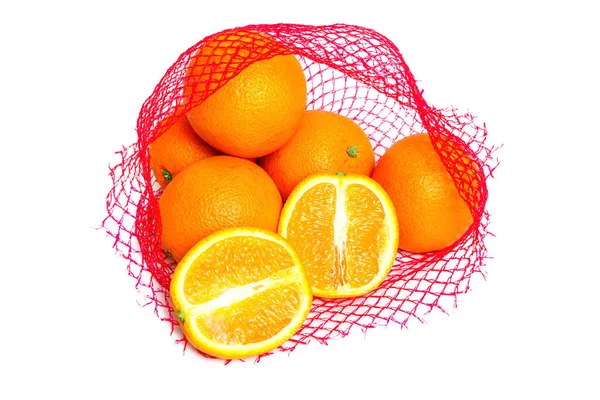 新鲜多汁的橙子装在红色网袋中 白色背景隔离 一个橙子切成两半 — 图库照片