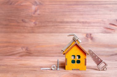 Küçük ölçekli ahşap ev modeli ve el aletleri heykelcikler ve bağlayıcılar kopya alanı olan ahşap bir arka planda izole edilmiş..