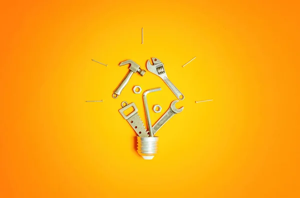 様々なハンドツールやファスナーの小さなスチール製のレプリカから作られた電球の形は すべて活気のあるオレンジの背景に配置されました Diy 手仕事 建設およびエンジニアリング関連の概念 — ストック写真
