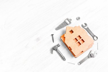 Ahşap ev parçaları ve küçük çelik el aletleri kopyalar beyaz ahşap bir masaya yerleştirilmeye hazır..