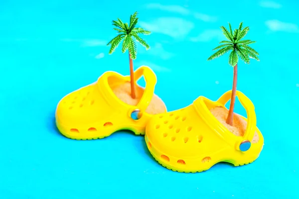 Yellow Clogs Sand Toy Palm Trees Isolated Blue Background Vivid — Stock Photo, Image
