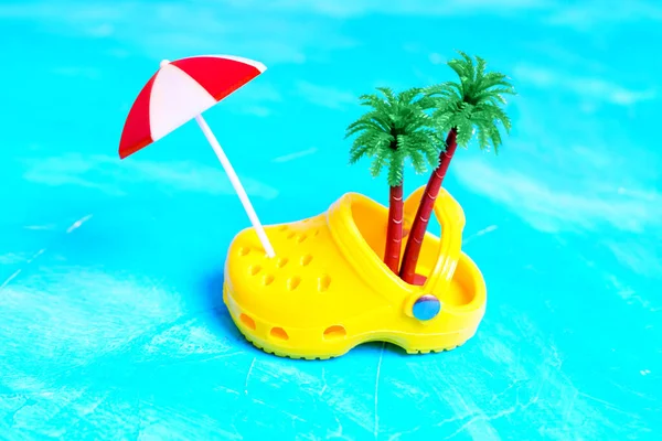 带有玩具棕榈树的迷你黄色塞子 以及放在浅蓝色纹理背景上的太阳伞 代表着一个沙洲和海洋的理念 — 图库照片