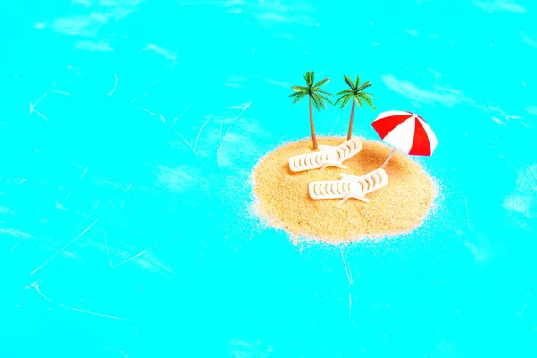 小沙堆形成的海滩被蓝色的背景隔离 装饰着一对玩具海滩躺椅和玩具棕榈树 捕捉着平静海滩的本质 放松和逃离 — 图库照片