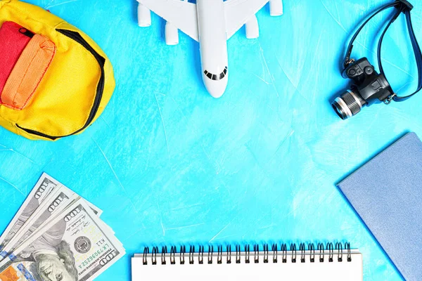 Toy airplane model with traveling essentials and accessories arranged on a blue background with copy space in the center.