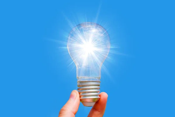 Strålande Glödlampa Hålls Stadigt Handen Isolerad Blå Bakgrund Problemlösning Och — Stockfoto