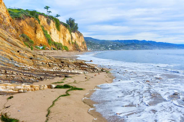 Malibu, Kaliforniya 'da kayalık bir uçurum ve okyanus dalgalarının yer aldığı çarpıcı bir kıyı manzarası.