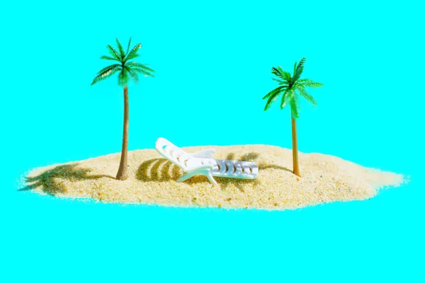 迷你世界的构成 玩具海滩的日光浴床 落在一小堆沙地上的玩具棕榈树之间 与海洋中一个遥远的岛屿相映成趣的蓝色背景相映衬 — 图库照片