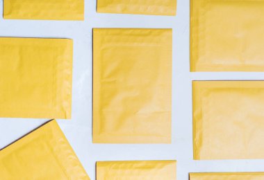 Yukardan aşağıya, beton bir masanın üzerine yerleştirilmiş yumuşak, sarı zarflar..