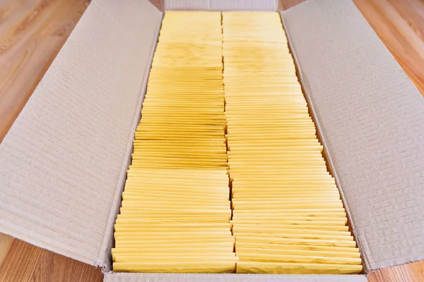 木製の床に置かれた黄色のパッド入り封筒で満たされたオープン配送ボックスのクローズアップ — ストック写真