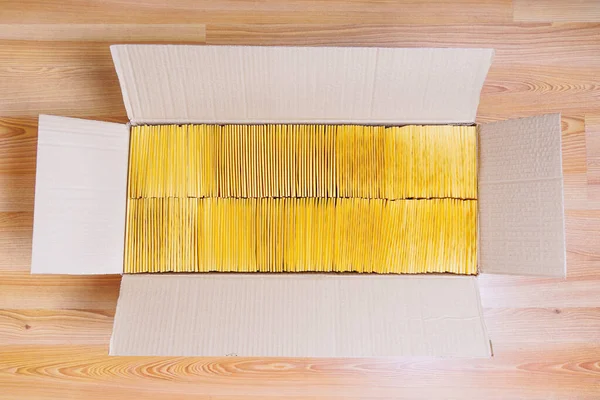 きれいに配置されたパッド入り黄色の封筒で満たされたオープンボックスと木製の床に配置されます 電子商取引の概念 — ストック写真