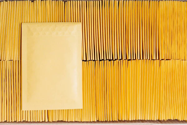 Zbliżenie Pudełka Kartonowego Wypełnionego Wyściełanymi Kopertami Jedną Żółtą Pocztą Umieszczoną — Zdjęcie stockowe