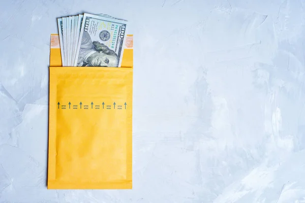 stock image Close-up view of a pile of crisp one hundred dollar bills neatly fanned inside a vibrant yellow envelope placed on a concrete table with copy space. Financial transactions and monetary gains concept.