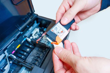 Yazıcıya yerleştirmeden önce yeni bir mürekkep kartuşunun koruyucu bandını çıkartırken yakın plan görüntüsü.