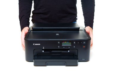 Kyiv, Ukrayna - 20 Temmuz 2023: İki eli de temiz beyaz bir zemin üzerinde modern bir Canon mürekkep jeti yazıcısı tutan kişi.