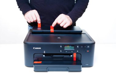 Kyiv, Ukrayna - 20 Temmuz 2023: Beyaz bir masa üzerindeki yepyeni Canon Inkjet yazıcısından canlı turuncu nakliye etiketleri çıkartılıyor.