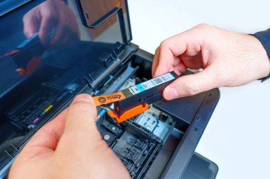 Kyiv, Ukrayna - 20 Temmuz 2023: Kurulumdan önce erkek ellerinin yeni bir Canon mürekkep jeti yazıcı kartuşundan koruyucu etiketi çıkarmasının ayrıntılı görünümü.