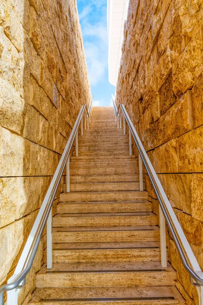 爬上两道石墙之间狭窄的通道中的台阶 通向充满活力的蓝天 — 图库照片