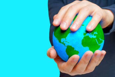 İnsan boş mavi bir tuvale karşı yeşil kıtaları olan bir küre tutar. Çevreye adanmışlık kavramı.