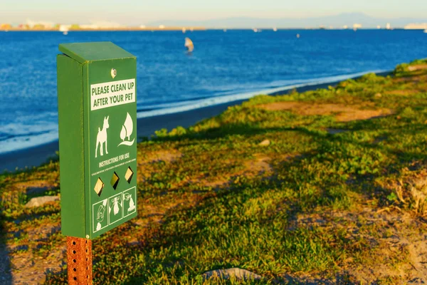 Dedicated pet waste disposal station with bags stands ready for use by pet owners at Cabrillo Beach, Los Angeles.
