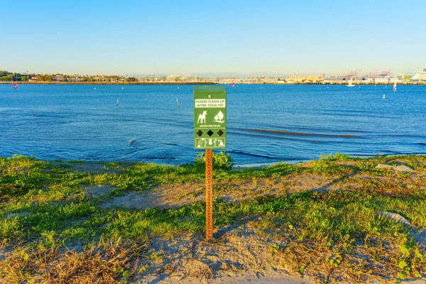 Dispenser with pet waste bags stands on the shore of Cabrillo Beach in Los Angeles, encouraging responsible pet ownership and cleanliness in the beautiful coastal area.