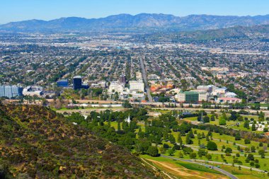 Hollywood tepelerinden görülen ikonik Forest Lawn Memorial Park 'ın bir kısmıyla Los Angeles şehir manzarası..