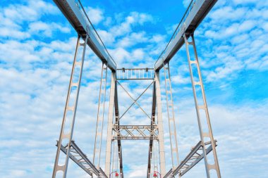 Köprü inşaatı, beyaz bulutlarla süslenmiş açık mavi gökyüzünün tuvaline kurulmuştur..