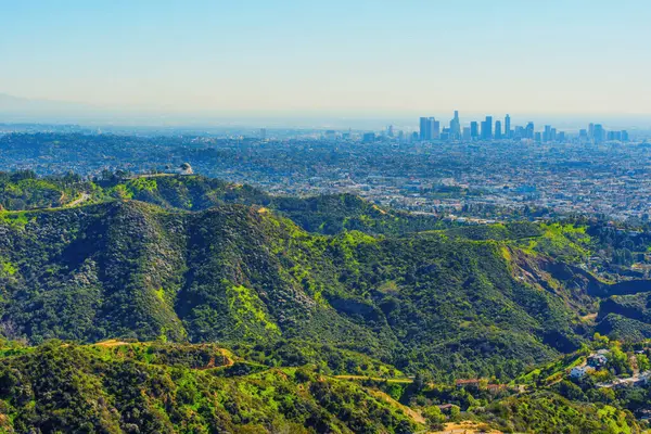 Gökyüzü perspektifi tepelere kurulmuş ikonik Griffith Gözlemevi 'ni yakalıyor. Ufukta genişleyen Los Angeles şehri var..