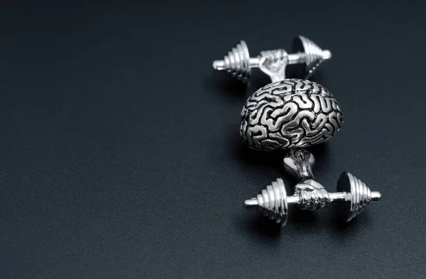 Creative brain workout concept. Steel copy of a human brain training with weights isolated on black.
