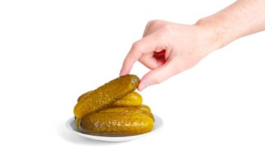 Erkek el zarif bir şekilde bir tabaktan salatalık turşusu alır, el değmemiş beyaz bir arka plan üzerine kurulur..