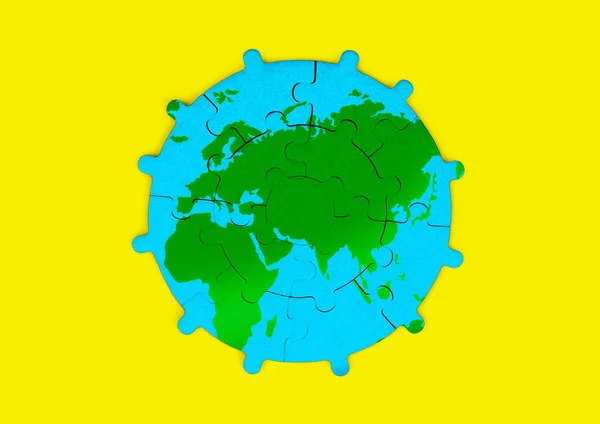 Sun-shaped jigsaw puzzle depicts a world map with green continents and blue oceans isolated on yellow background. Education, business and environmentalism related concept.