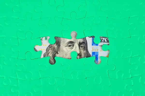 ジグソーパズルの背景は その空のスペースを通して100ドル紙幣の一部を明らかにします 財務計画 富裕管理コンセプト ストック画像