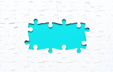 Merkezinde birkaç eksik parça bulunan boş yapboz parçaları birleştirildi ve altta yatan mavi arkaplan etrafında bir çerçeve oluşturuldu. Birlik ve ilerleme ile ilgili kavram.