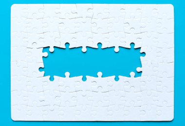 Ortasında el değmemiş mavi bir arkaplanda düzenlenmiş birkaç eksik parçayla birleştirilmiş boş bir yapboz. Birlik ve ilerleme ile ilgili kavram.