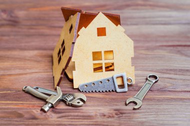 Tahta bir arka planda, temel el aletlerinin küçük çelik kopyalarıyla çevrili parçalanmış ahşap bir hortum modelinin yakın çekimi..