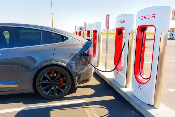 White Hills, Arizona - 14 Nisan 2024: Tesla Model X Car, Manzarasında Tesla logosu olan bir süperşarj istasyonuna takıldı