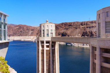 Büyük Kanyonlar çeşitli kaya yapıları ve kanyon duvarları günbatımında gösteriliyor, mavi gökyüzü canlı bir zemin oluşturuyor..