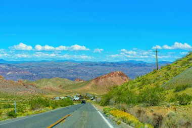Asfalt yol, Nevada çölünün göbeğinde terk edilmiş bir yerleşim yerine gidiyor. Kurak araziler ve engebeli arazilerle çevrili..