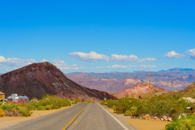 Nevada 'nın büyüleyici manzarası, yolun ufukta durmaksızın uzandığı dağ zirveleri ve gök mavisi gökyüzünün ihtişamıyla çerçevelenmiş..