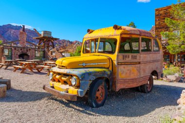 Nelson, Nevada - 15 Nisan 2024: Aşınmış gövdesi ve kayıp pencereleri olan eski model sarı Ford otobüs.