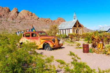 Nelson, Nevada - 15 Nisan 2024 Terk edilmiş kırsal Plymouth arabası eski ahşap bir kilisenin yanında hayalet madencilik yerleşiminde park edilmiş.