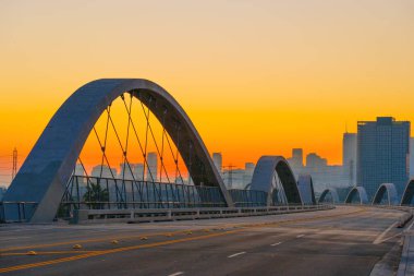 Gün batımında Los Angeles 'taki 6. Cadde Köprüsü' nün sakin manzarası köprünün belirgin kemer deseni ve gökyüzünün sıcak renklerine karşı büyüleyici kentsel siluetler..