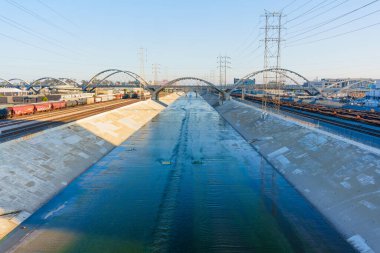 Los Angeles, Kaliforniya - 12 Nisan 2024: Sanayi bölgesindeki ikonik 6. Cadde Köprüsü 'ne doğru uzanan beton bir kanal üzerinden akan Los Angeles Nehri