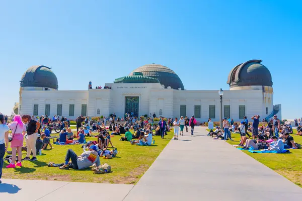 Los Angeles, Kaliforniya - 8 Nisan 2024: Griffith Park 'ta toplanan kalabalık, açık mavi bir gökyüzünün altında ikonik Griffith Gözlemevi ile bir güneş tutulmasına tanıklık ediyor.