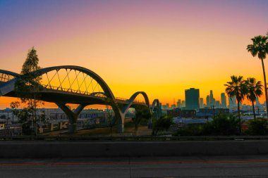Los Angeles, Kaliforniya - 12 Nisan 2024: 6. Cadde Köprüsü 'nün altından büyüleyici günbatımı manzarası, sıcak, altın rengi bir ışıkla yıkanmış şehir manzarasını gözler önüne seriyor