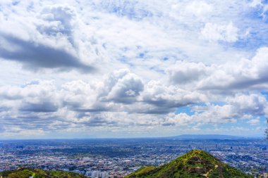 Runyon Kanyon Parkı 'ndaki bir tepenin üstündeki sakin toprak patika seyircinin bakışlarını şehir manzarasına, gökyüzüne ve ötesindeki bulutlara çekiyor..