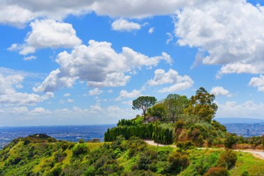 Runyon Canyon Parkı 'ndaki bir tepenin üstündeki ev mavi gökyüzüne karşı kalın beyaz bulutlarla kaplı..