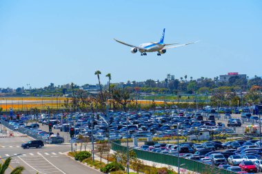 Los Angeles, California - 9 Nisan 2024: Sıkıca doldurulmuş LAX park alanlarının yakın görüntüsü, üzerinde uçan bir uçak, yer ve hava yolculuğunun yakınlaşmasını gösteriyor.