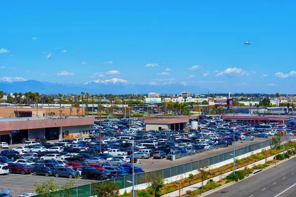 stock image Los Angeles, California - April 9, 2024: Airplane flying over the open-air LAX Economy Parking lot with a clear blue sky backdrop, capturing the essence of travel and transit.